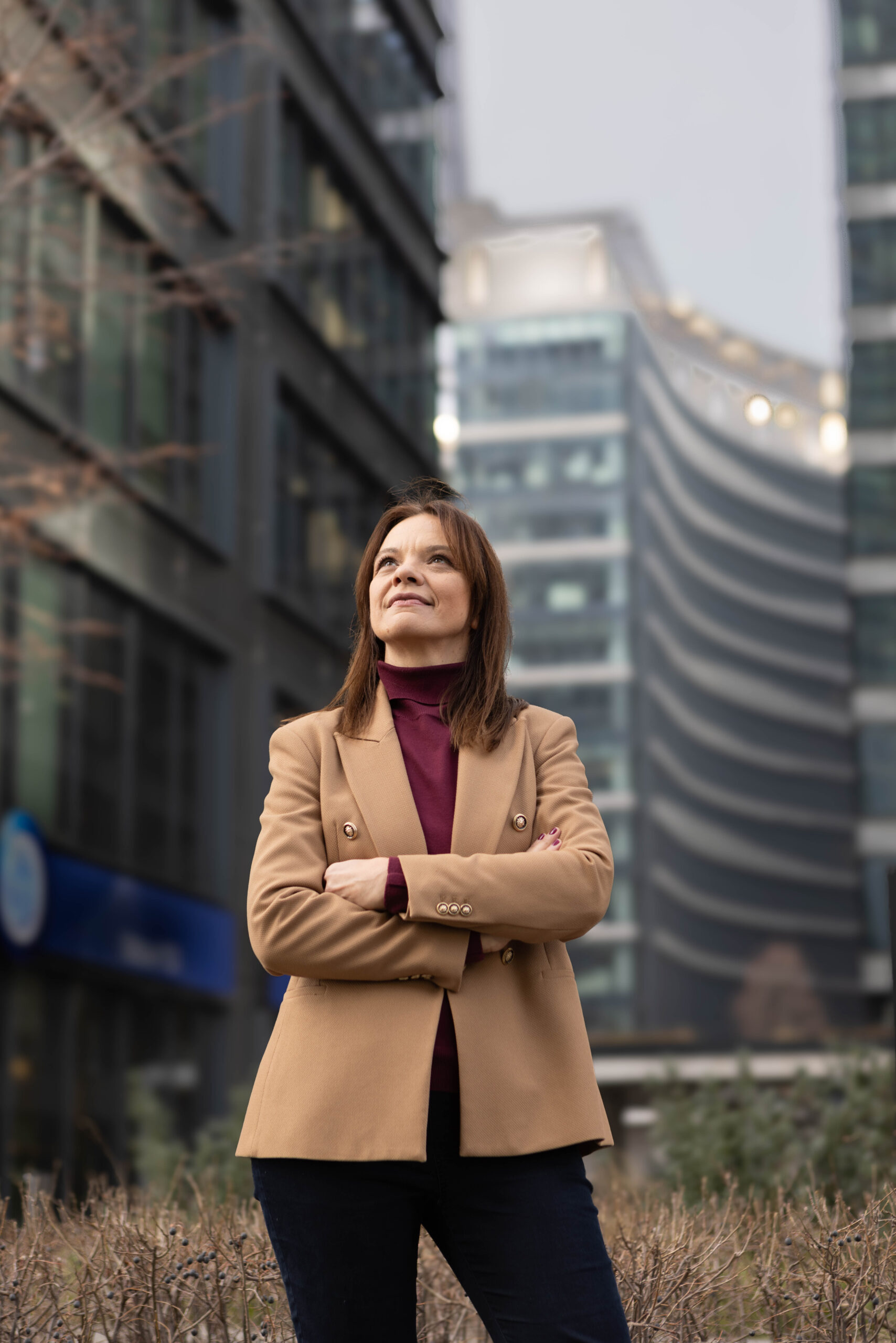 5. Kobieta biznesu pracująca w korporacji w Warszawie na tle biurowców, uśmiechnięta i pewna siebie