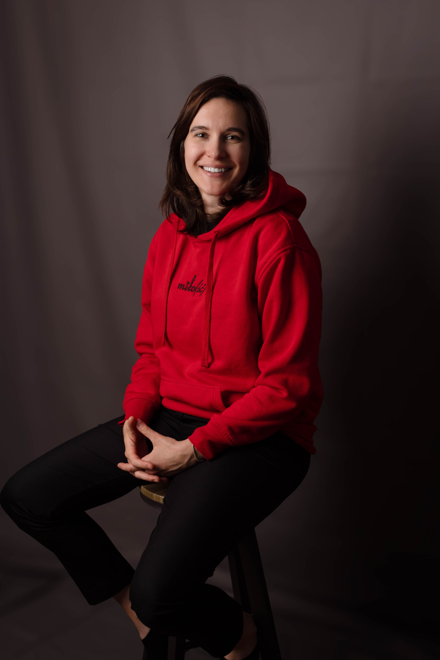 Portret studyjny dziewczyny w czerwonej bluzie z uśmiechem patrzącej w obiektyw