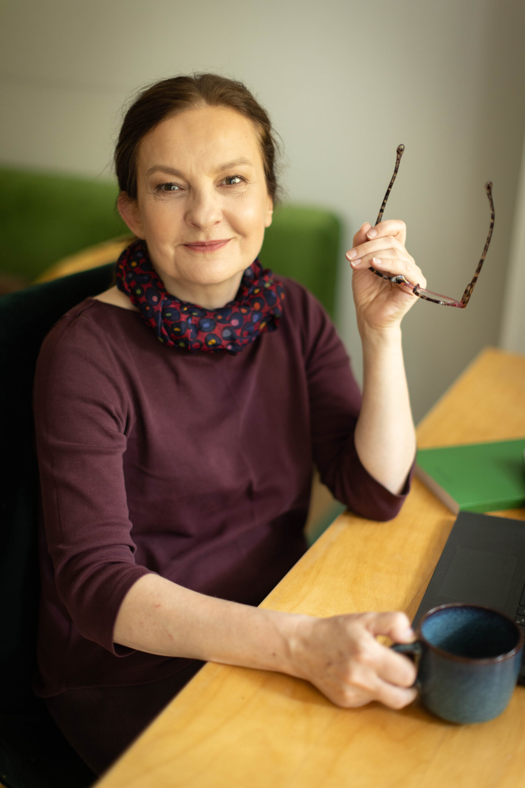 Rudowłosa kobieta w czerwonych okularach siedzi przy biurku