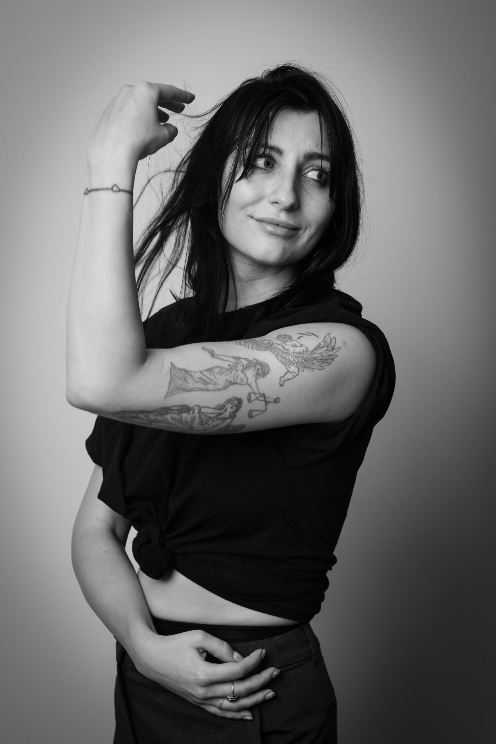 Młoda brunetka w czarnej koszulce z tatuażami, zdjęcie czarno-białe