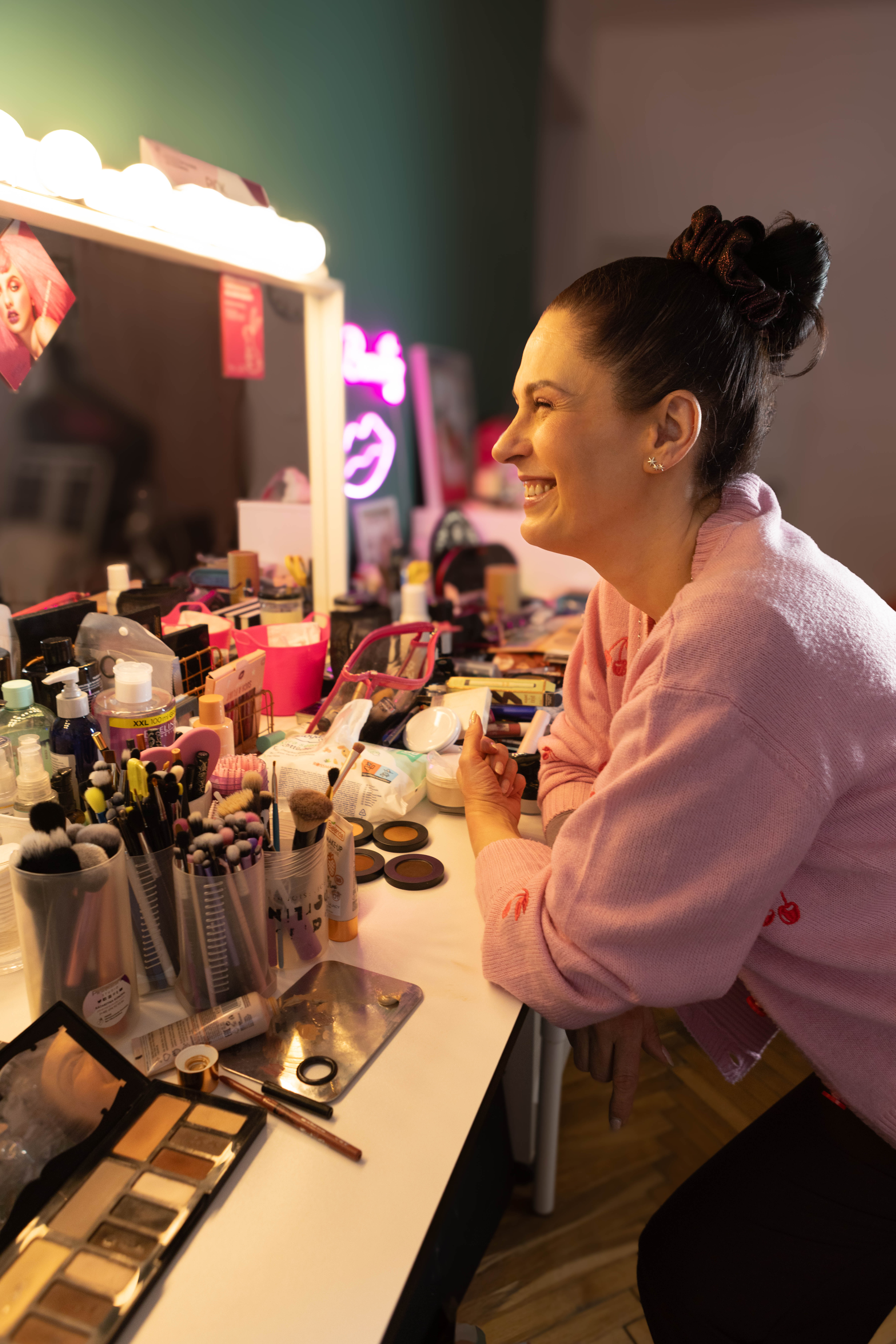 Ciemnowłosa kobieta makijażystka uśmiecha się do lustra